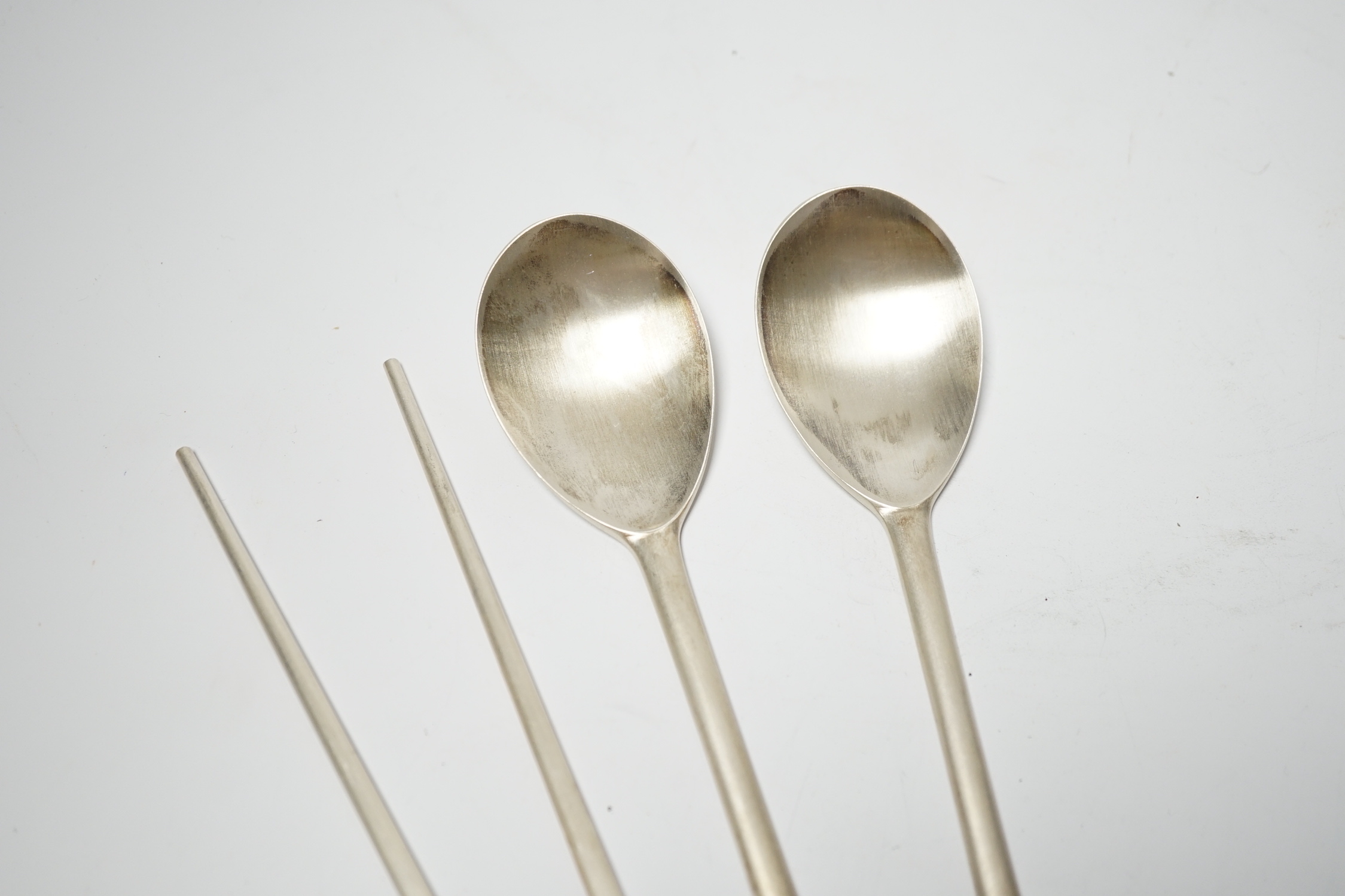 A Korean 990 standard white metal pair of chopsticks, 20cm and two matching spoons with enamelled decoration.
